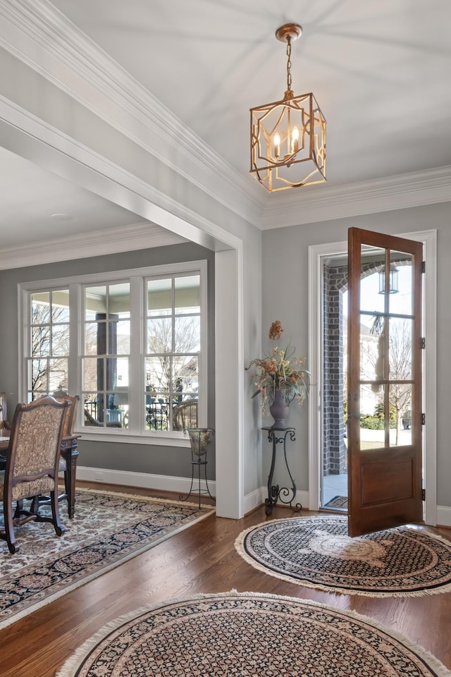 foyer entrance featuring baseboards, a chandelier, wood finished floors, and ornamental molding