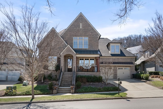 view of front of house featuring metal roof, brick siding, driveway, stairway, and a standing seam roof