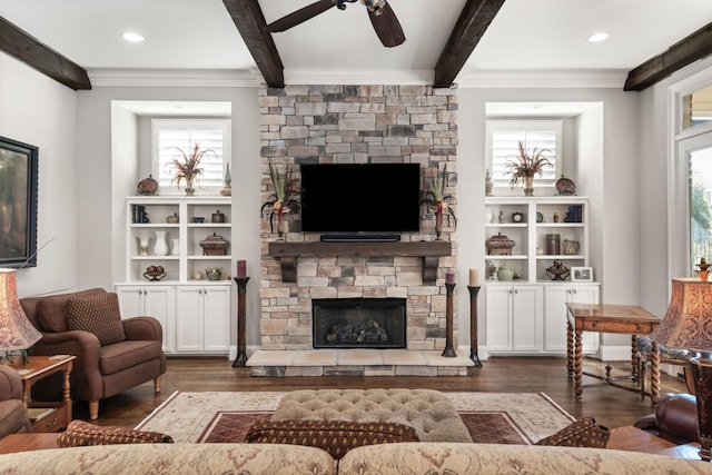 living area with wood finished floors, beam ceiling, and a stone fireplace