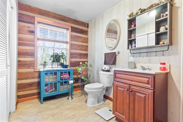 bathroom with toilet, wood walls, and vanity