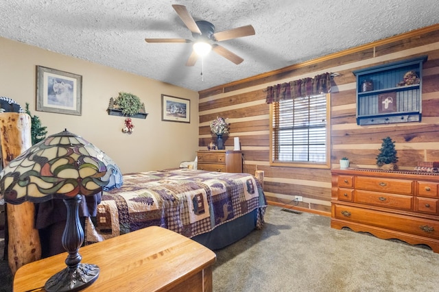 bedroom featuring visible vents, ceiling fan, carpet, a textured ceiling, and wood walls