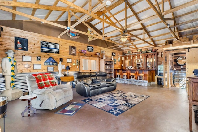 living room featuring wooden walls, ceiling fan, finished concrete floors, and high vaulted ceiling