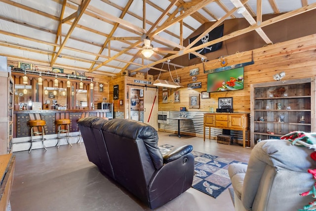 living room with high vaulted ceiling, a dry bar, a ceiling fan, wood walls, and concrete flooring