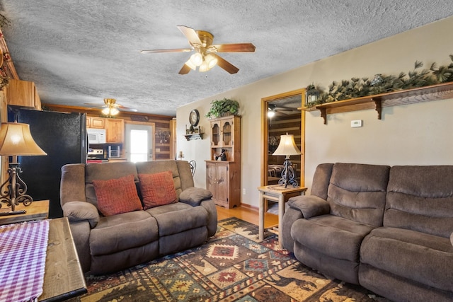 living area featuring a textured ceiling, a ceiling fan, and light wood-style floors