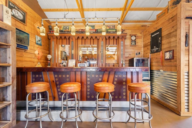 bar with finished concrete flooring, a dry bar, and wood walls