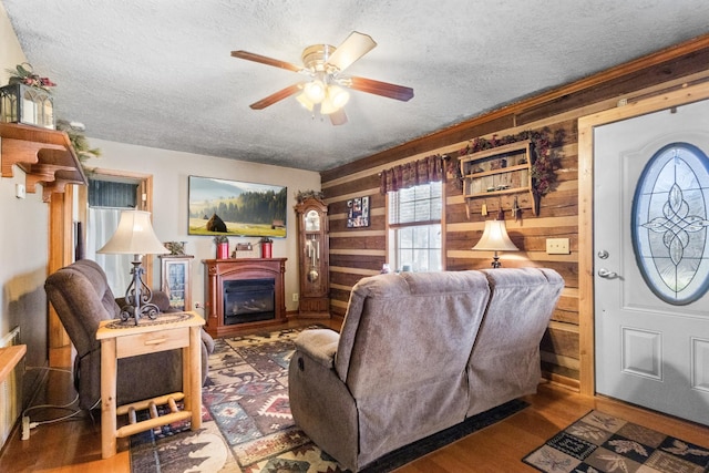 living room with a textured ceiling, wooden walls, and wood finished floors