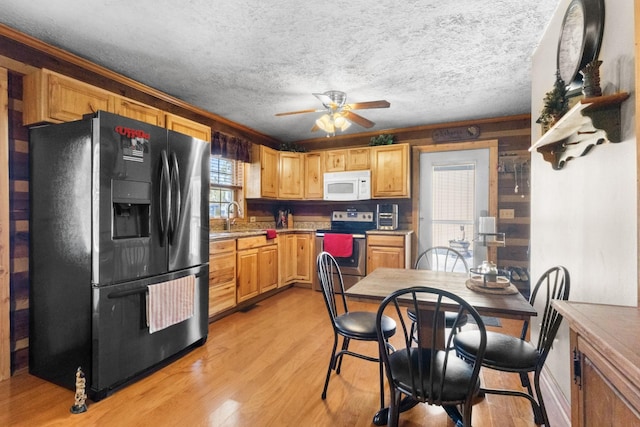 kitchen with electric stove, white microwave, black refrigerator with ice dispenser, light wood-type flooring, and a sink