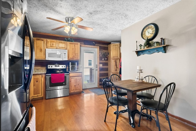 kitchen with stainless steel appliances, ceiling fan, a textured ceiling, and light wood finished floors