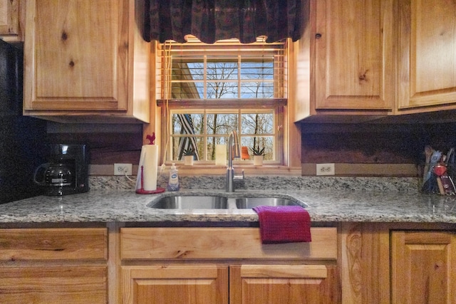 kitchen featuring light brown cabinets, a sink, and light stone countertops