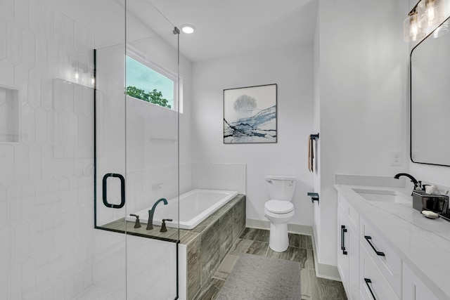 bathroom featuring toilet, a shower stall, vanity, baseboards, and a bath