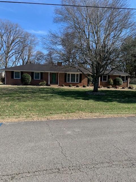 single story home with brick siding and a front yard