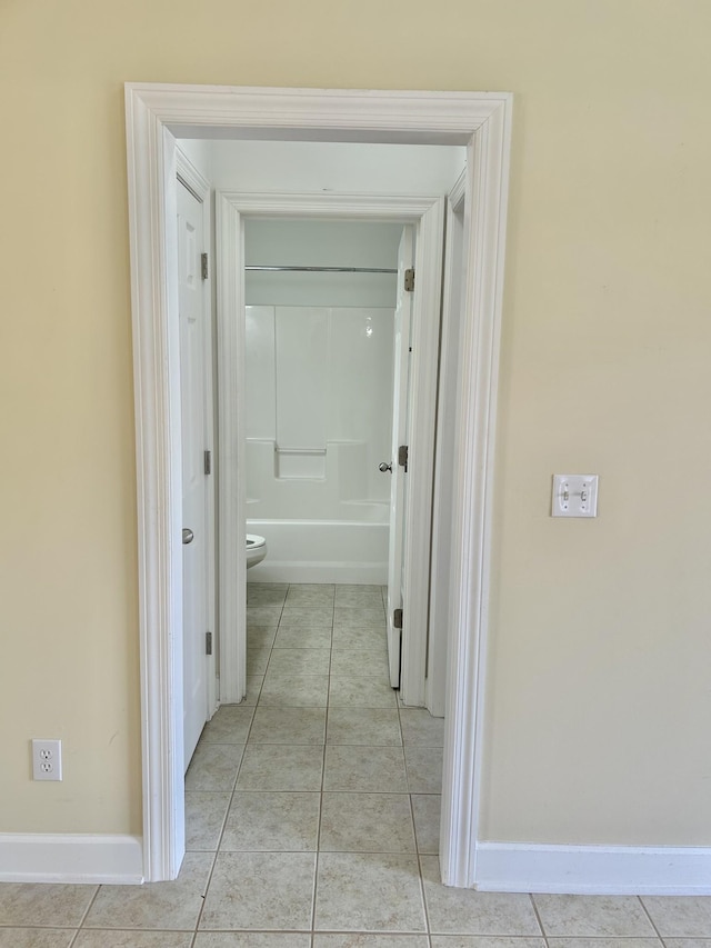 corridor featuring baseboards and light tile patterned floors
