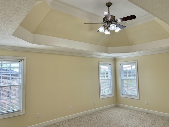 empty room with ceiling fan, light carpet, baseboards, a tray ceiling, and crown molding