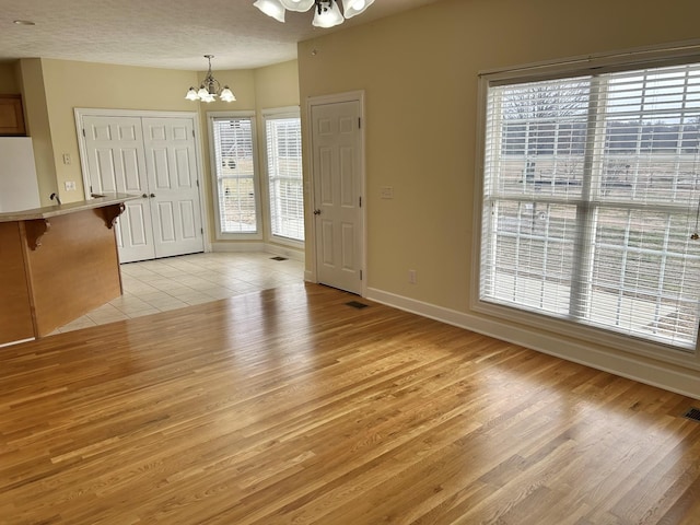 interior space with light tile patterned floors, a textured ceiling, baseboards, and an inviting chandelier