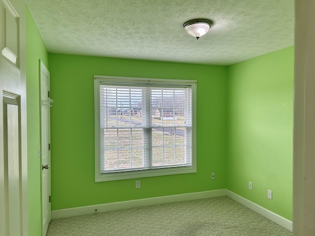 carpeted spare room with baseboards and a textured ceiling