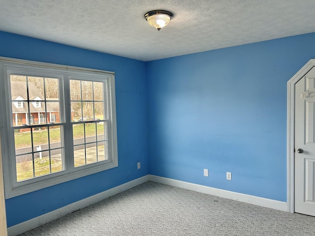 carpeted empty room featuring a textured ceiling and baseboards
