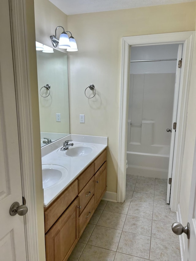 bathroom with double vanity, tile patterned flooring, a sink, and baseboards