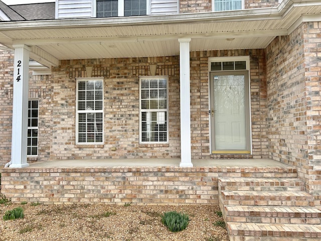 view of exterior entry with covered porch and brick siding