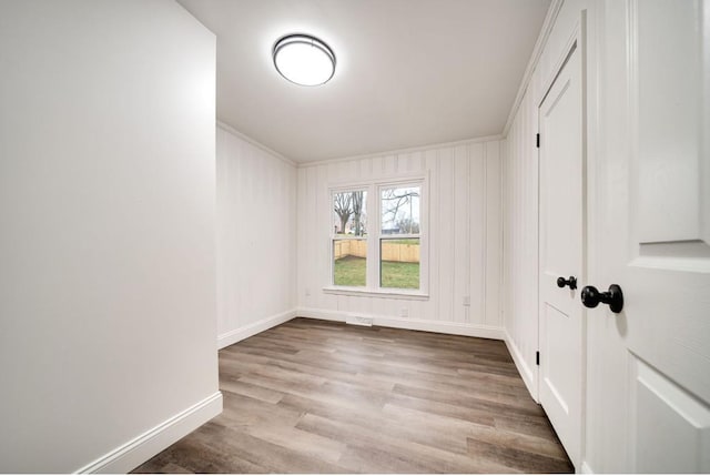 unfurnished bedroom with ornamental molding, wood finished floors, and baseboards