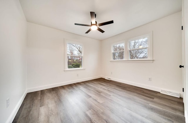 empty room featuring dark wood-style floors, visible vents, and baseboards