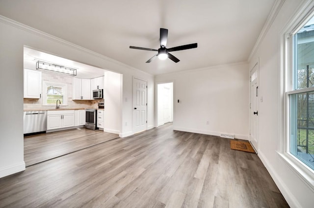 unfurnished living room with visible vents, crown molding, and wood finished floors