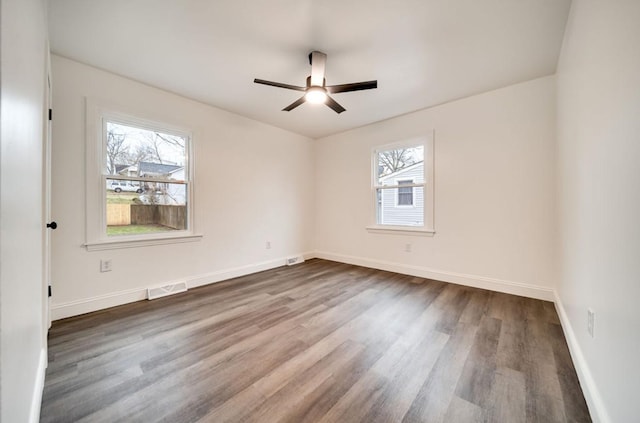 unfurnished room with dark wood-style floors, ceiling fan, visible vents, and baseboards