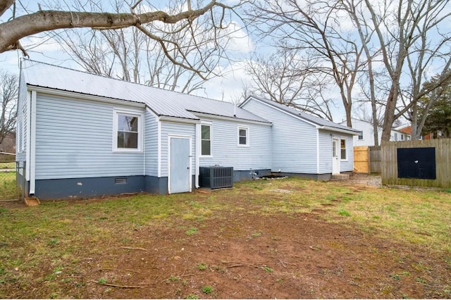 rear view of property featuring a lawn, crawl space, central AC, fence, and metal roof