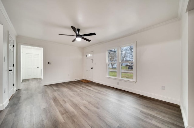 unfurnished living room with ceiling fan, ornamental molding, wood finished floors, and baseboards