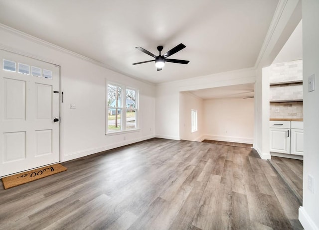 unfurnished living room with a ceiling fan, crown molding, and wood finished floors