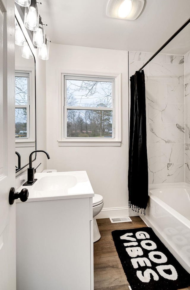 full bathroom featuring visible vents, toilet, wood finished floors, shower / bathtub combination with curtain, and vanity