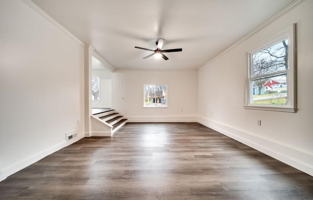 spare room featuring crown molding, visible vents, dark wood-type flooring, ceiling fan, and baseboards