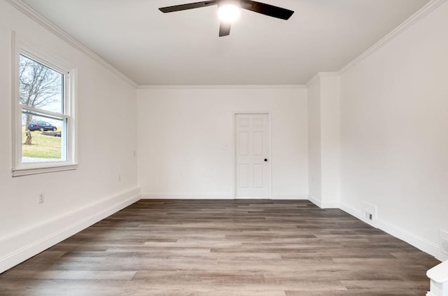 spare room with crown molding, baseboards, and wood finished floors