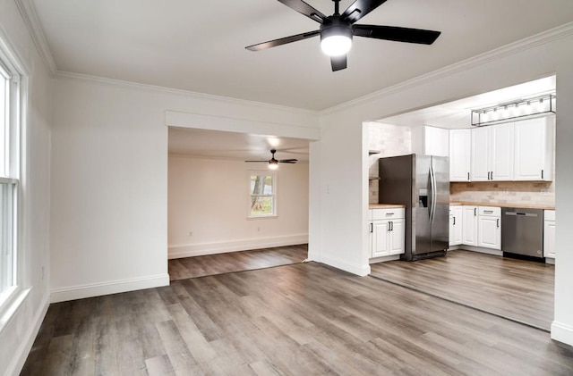 kitchen featuring appliances with stainless steel finishes, light countertops, ornamental molding, and wood finished floors