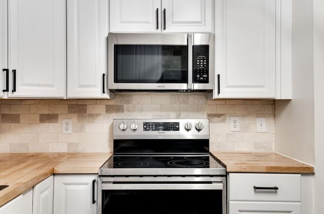 kitchen featuring stainless steel appliances, butcher block counters, decorative backsplash, and white cabinets