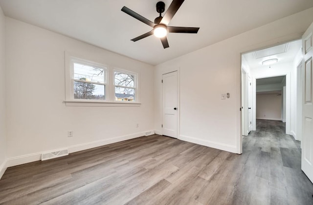 unfurnished bedroom featuring baseboards, wood finished floors, visible vents, and attic access