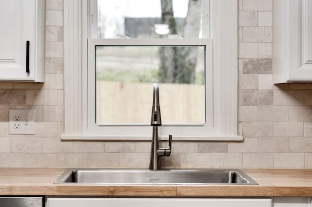 kitchen featuring tasteful backsplash, white cabinets, dishwasher, wood counters, and a sink