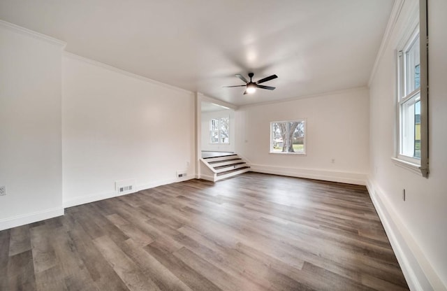 spare room featuring ceiling fan, dark wood-type flooring, visible vents, baseboards, and ornamental molding