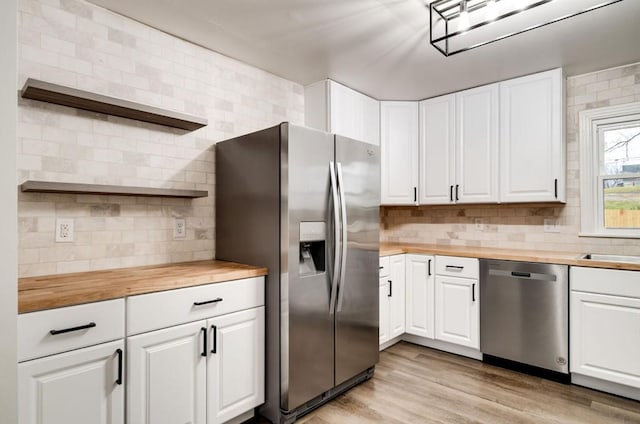 kitchen with stainless steel appliances, butcher block counters, light wood-style flooring, and open shelves