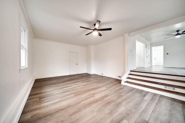 empty room with crown molding, visible vents, a ceiling fan, and wood finished floors