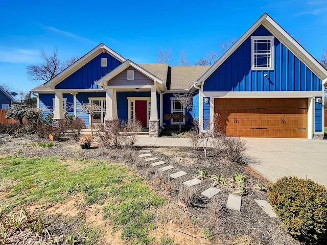 view of front of property with driveway, stone siding, a garage, and board and batten siding