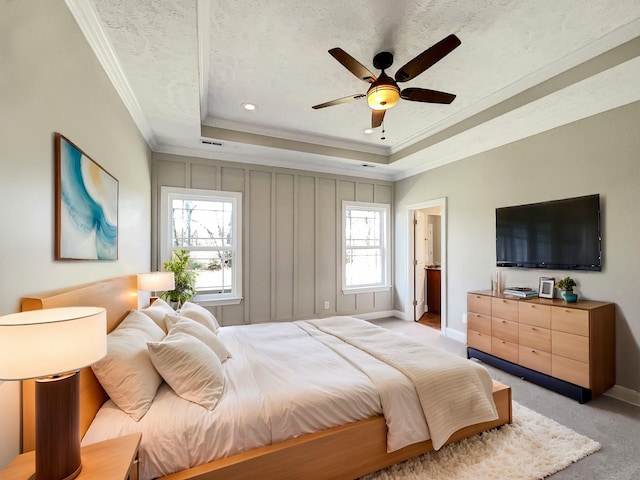 bedroom with a raised ceiling, light carpet, crown molding, and baseboards