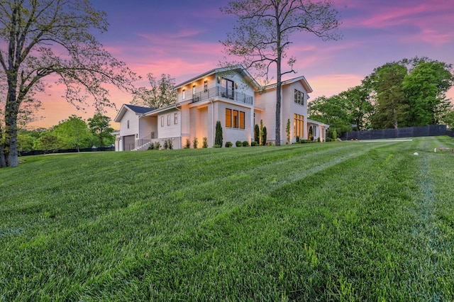 rear view of property with a lawn, stucco siding, a balcony, and an attached garage