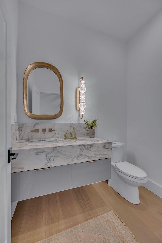 half bath featuring toilet, wood finished floors, and vanity