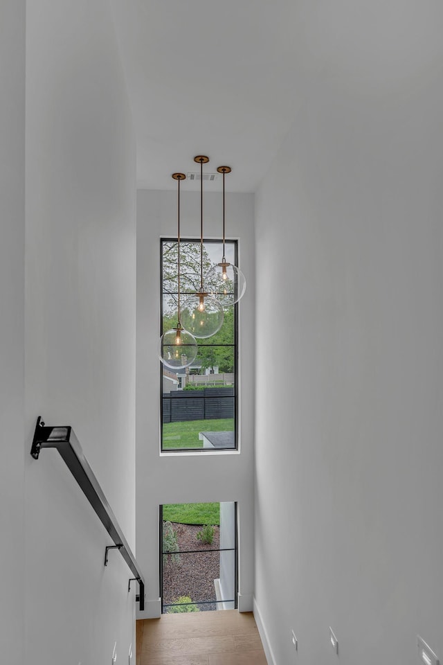stairway featuring baseboards, wood finished floors, and a notable chandelier