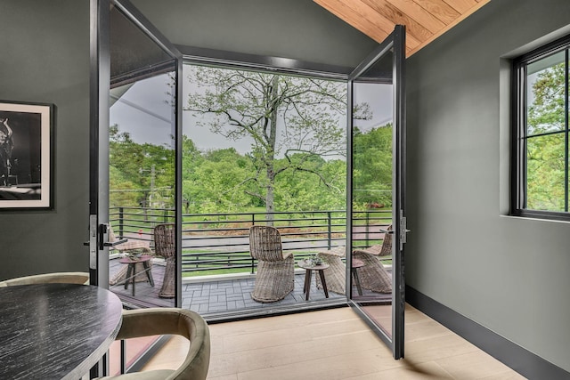 doorway to outside featuring wood finished floors, vaulted ceiling, a wealth of natural light, and wood ceiling