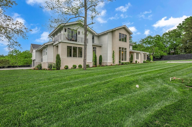 view of front of house with a front yard, stucco siding, and fence