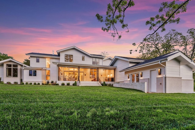back of house at dusk with a lawn and a ceiling fan