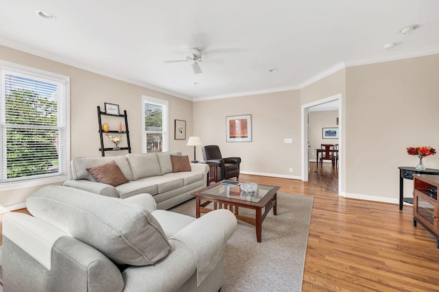 living room with crown molding, light wood finished floors, a ceiling fan, and baseboards