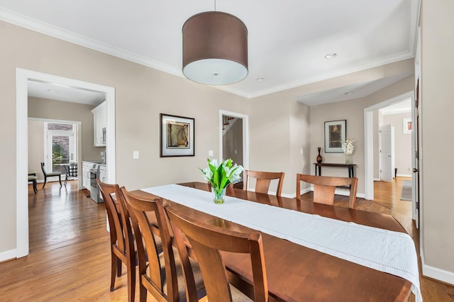 dining room with ornamental molding, light wood-style flooring, and baseboards