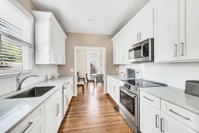 kitchen featuring stainless steel appliances, white cabinets, a sink, and light wood finished floors